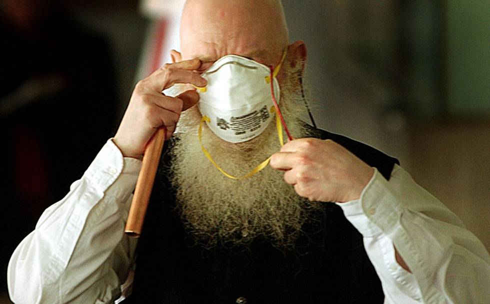 “Nuestra mente rellena lo que no vemos”: por qué parecemos más guapos con mascarilla 2 Un empleado de un hospital de Toronto se pelea con su mascarilla durante la epidemia de SARS en 2003.