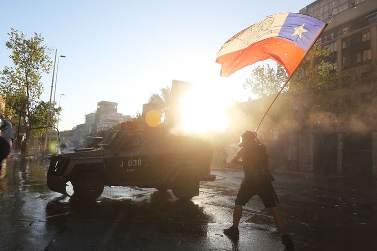 Más de 37.000 funcionarios chilenos piden la ayuda al desempleo y el Gobierno les exige devolverla 2 Un manifestante ondea una bandera chilena, este viernes en una protesta en vísperas del plebiscito constitucional.