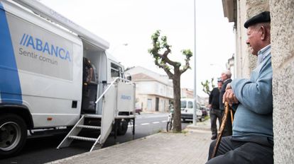 La España vacía se rebela contra el cierre de oficinas bancarias 2 Un hombre sentado ante una oficina móvil de Abanca en Albarellos de Monterrei (Ourense), en 2019.