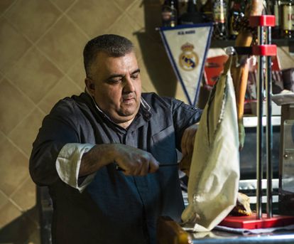 Recuerdos de mi primer ElClásico 18 Gregorio Pifarre, dueño del Casal d'Alfés, el único restaurante el pueblo, corta una loncha de jamón. De fondo, el banderín del Real Madrid.